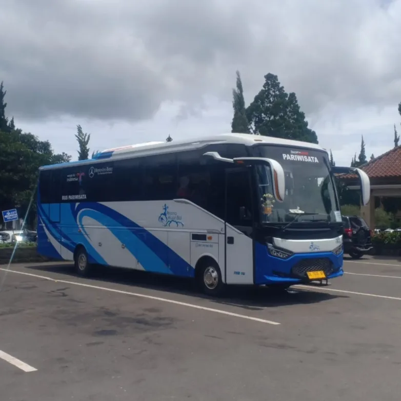 Bus pariwisata Mercedes-Benz bodi putih biru milik PAB Trans terparkir di halaman